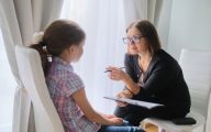 Woman social worker talking to girl. Child psychology, mental health.