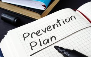 Prevention plan written in a note pad and documents.