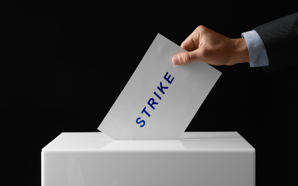 Man putting his vote with word Strike into ballot box on black background, closeup