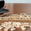 strike ballot word or concept represented by wooden letter tiles on a wooden table with glasses and a book