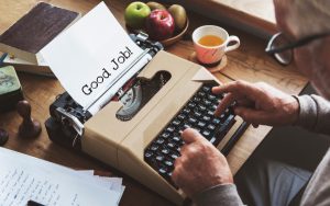 Person typing 'good job! on a typewriter
