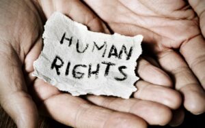 Hand holding a piece of parchment with the words 'human rights' written on it