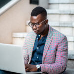 A black social worker looking contemplative while working at laptop