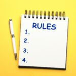 Notebook with list of rules and pen on yellow background, flat lay
