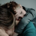 sad child hugging parent with their head turned away