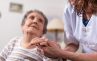 Nurse holding the hand of an older woman in a care home