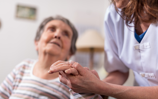 Nurse holding an older woman's hand in a nursing home