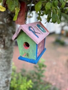 painted bird house hanging from a tree in the garden at Jasmine Mother's Recovery