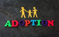 The word 'adoption' spelt out in coloured letters beneath cut-outs of a family