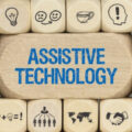 Wall of blocks with symbols on them and a central one carrying the words 'assistive technology' in blue