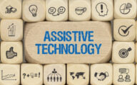 Wall of blocks with symbols on them and a central one carrying the words 'assistive technology' in blue