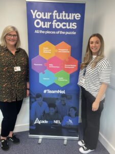 Ellis and Katy at North East lIncolnshire council, in front of a pull up banner that says 'your future, our focus'