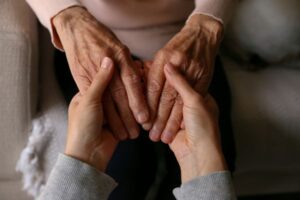 Cropped shot of elderly woman and female geriatric social worker holding hands. Women of different age comforting each other.