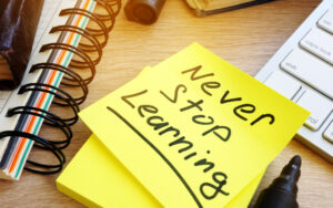 Never stop learning written on a memo stick. Lifelong learning concept.