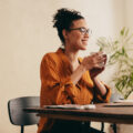 Woman having coffee and looking at laptop. Female taking a coffee break while working from home.