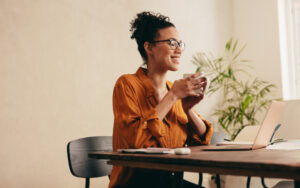 Woman having coffee and looking at laptop. Female taking a coffee break while working from home.