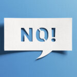 No sign showing negative answer or decision, disagreement, rejection, refusal or contradiction. Word no on cutout paper speech bubble on blue background.