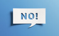 No sign showing negative answer or decision, disagreement, rejection, refusal or contradiction. Word no on cutout paper speech bubble on blue background.