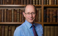 Economist Andrew Dilnot standing in a library