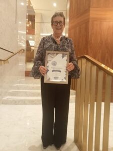 Pat Curtis wearing a grey blouse and black trousers and holding her silver award for Practice Educator of the Year in the Social Worker of the Year Awards.