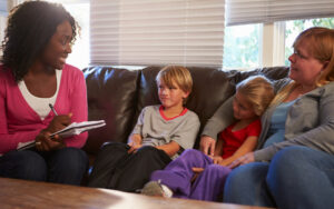 Social Worker Talking To Mother And Children At Home