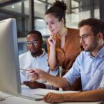 Three colleagues, two males and one female, looking at a computer screen