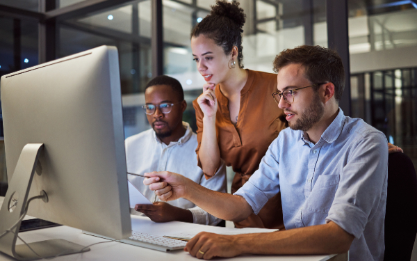 Three colleagues, two males and one female, looking at a computer screen