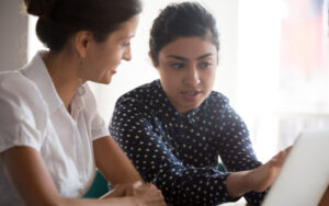 Two women talking to each other at their desk in an office