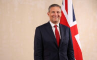 James Timpson, at the time minister for prisons, standing in front of a union jack