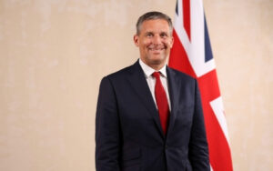 James Timpson, at the time minister for prisons, standing in front of a union jack