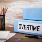 Overtime, Office Binder on Wooden Desk. On the table colored pencils, pen, notebook paper