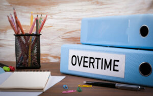 Overtime, Office Binder on Wooden Desk. On the table colored pencils, pen, notebook paper