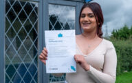 A young woman holding up a certificate for passing a course run by ASDAN