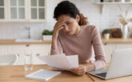 Woman looking stressed staring at a piece of paper that looks like a bill