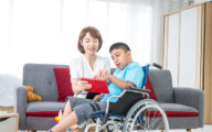 An advocate helping a disabled boy use a tablet