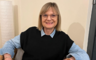 Professor Marian Brandon wearing a black wool vest and a blue shirt, smiling at the camera.