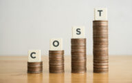 Piles of coins of increasing size with tiles spelling out the word 'cost' sitting on each