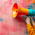 An orange and blue megaphone against a colourful, pink and blue, backdrop.
