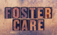 The words Foster Care concept and theme written in vintage wooden letterpress type on a grunge background.