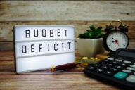 BUDGET DEFICIT letterboard text on LED Lightbox on wooden background