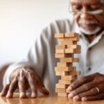 African American Senior man with dementia playing with wooden blocks in geriatric clinic or nursing home