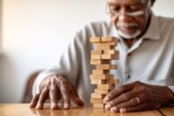 African American Senior man with dementia playing with wooden blocks in geriatric clinic or nursing home