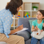 Child psychologist talking to child who is sitting on sofa