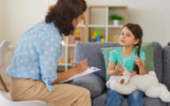 Child psychologist talking to child who is sitting on sofa