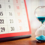 Page of calendar next to sand timer to symbolise passing of time