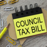 COUNCIL TAX BILL text on sticker on black paper on wooden background