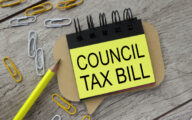 COUNCIL TAX BILL text on sticker on black paper on wooden background