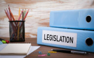 Legislation, Office Binder on Wooden Desk. On the table colored pencils, pen, notebook paper