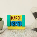 Image of march 31 on a wooden coloured calendar, next to sandtimer on white background
