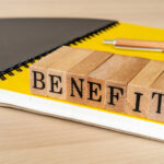 The word 'benefits' spelt out in blocks on top of the yellow page of a notepad